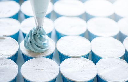 Squeeze the cream filling on the blue cupcake, soft focusの写真素材