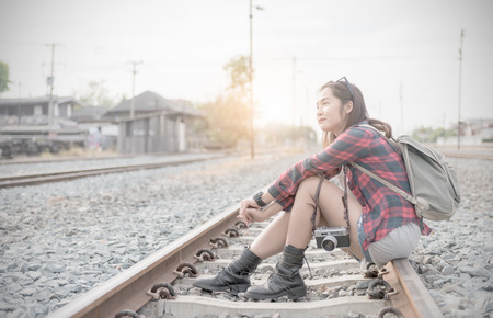 Hipster young girl waiting train on railway background and vintage tone, concept travel and leisure..の写真素材