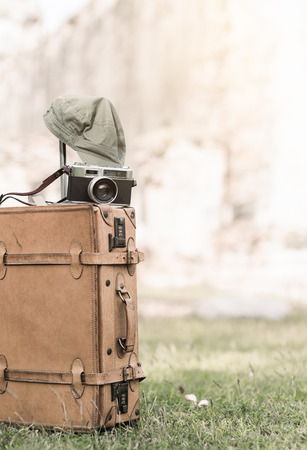 vintage camera on old baggage bag on grass, old temple background and vintage tone.の写真素材