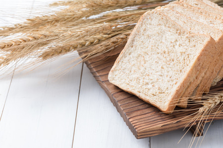 Slice wheat bread on white wood background, healthy food concept.