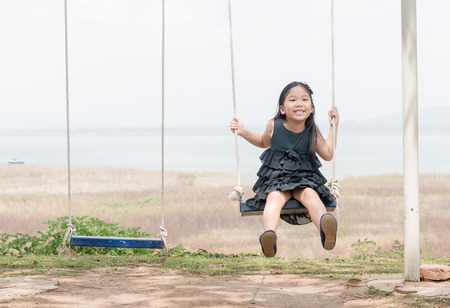 cute girl play swing seat on nature background, leisure conceptの写真素材