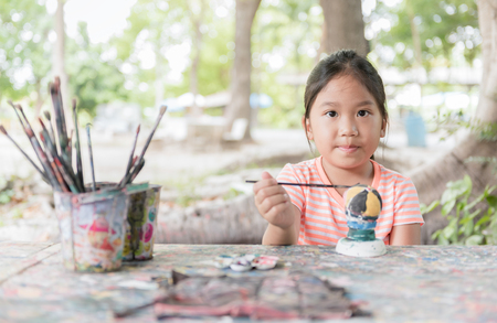 Child painting,cute little girl having fun to paint on stucco doll on nature background.の写真素材