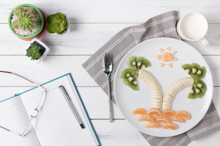 banana kiwi orange and melon on dish, white wood background top view and copy space..の写真素材