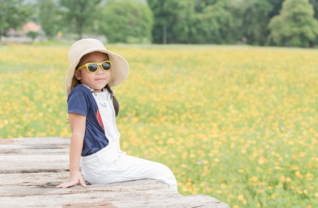 cute girl sit on wood and yellow flower background, travel concept.の写真素材
