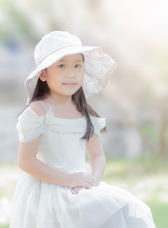 cute girl wear vintage white long dress with big hat on nature background, soft focus.の写真素材