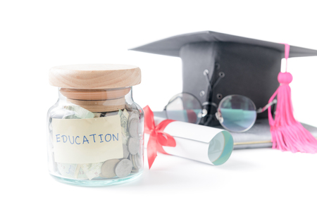education budget concept. education money savings in a glass jar with glasses, graduate hat and book isolated on white background.の写真素材