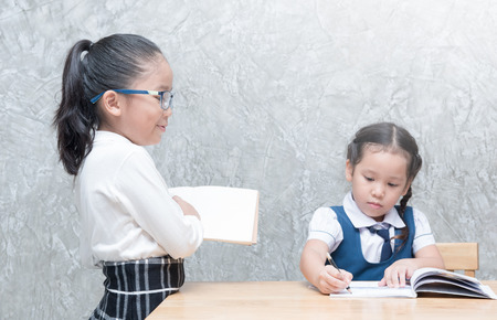 little teacher looking student to doing homework in classroom, education concept.の写真素材