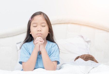 Little girl praying on bed. Little asian girl hand praying, Hands folded in prayer concept for faith,spirituality and religionの写真素材