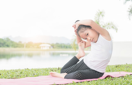 Happy cute girl playing gymnastic on outdoor park, exercise and healthy concept.の写真素材