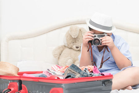 Happy fat boy take pictures from vintage camera. After prepared Travel accessories costumes in suitcase for the trip.の写真素材