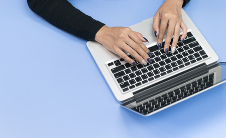 Top view of woman using laptop on blue desk, education conceptの写真素材