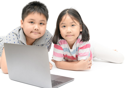 cute sister and young brother play laptop isolated on white background, education concept.の写真素材