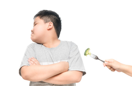 obese fat boy with expression of disgust against vegetables isolated on white background, Refusing food concept.の写真素材