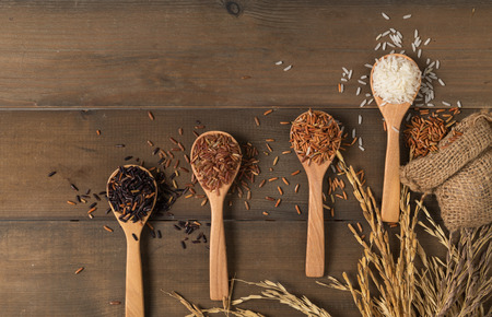 Row of white jasmine rice with various rice:  Rice berry, brown and thai red mixed rice on brown wooden background, organic rice and healthy foodの写真素材