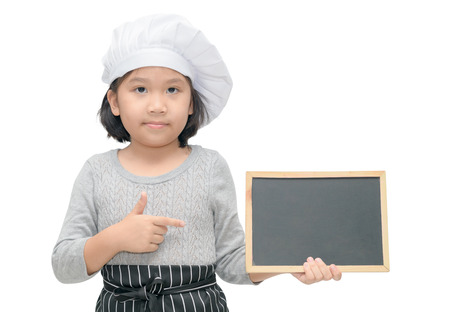 Little asian girl chef in uniform cook holding blackboard for in put text or menu, isolated on white background..の写真素材