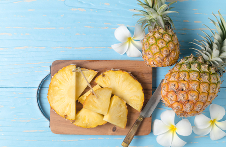 fresh sliced pineapple on wood block and blue wood background, summer fruits concept..