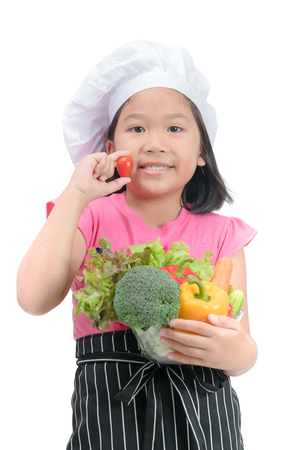 cute little girl chef smile and holding tomato with vegetables in bowl, healthy food concept..の写真素材