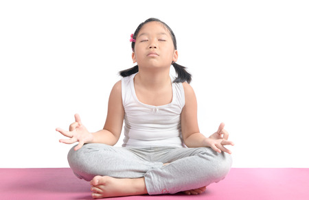 Asian cute girl sitting on floor meditating. Yoga isolated on white background. Lotus Position. Healthy concept.の写真素材