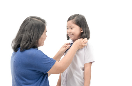 Mother dressing uniform student her daughter isolated on white background, back to school concept.の写真素材