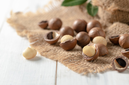 Shelled and unshelled macadamia nuts on white wood background.の写真素材