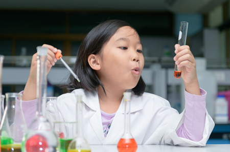 Happy little scientist in lab coat making experiment with test tube in chemical laboratory, science and education concept..の写真素材