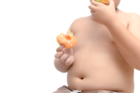 Obese fat boy is holding and eating donut isolated on white background, junk food and dieting concept.の写真素材