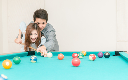 Happy couples are playing billiards in home, recreation and leisure concept.