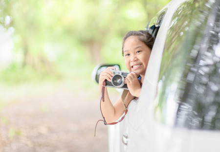 Cute girl take picture with vintage  camera from window car, travel conceptの写真素材