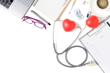 Top view of doctor desk table with stethoscope and red heart, coffee and laptop. Top view with copy space, flat lay..の写真素材