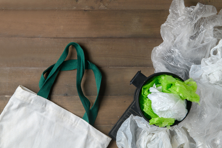 plastic bags in bin and canvas tote bag on wood background, refuse plastic or recycle and save environmental concept.の写真素材