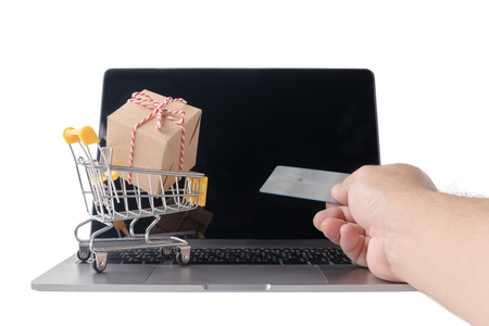 Man holding credit card    and Boxes in a trolley on a laptop keyboard isolated on whiteの写真素材