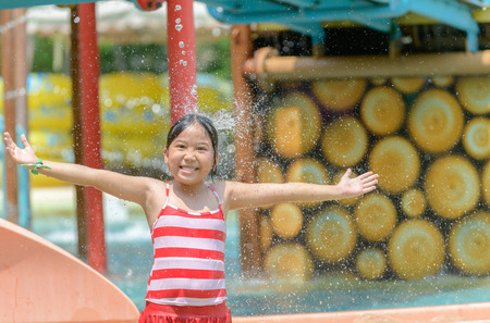 Happy little caucasian girl playing water at aquapark. summer vacation concept..の写真素材
