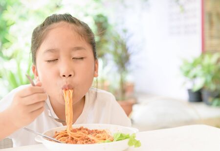 Happy girl enjoy eating spaghetti with pork sauce, food and healthy conceptの写真素材