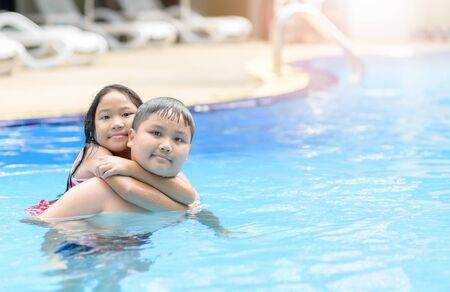 Brother and sister play water in swimming pool, exercise and recreation concept.