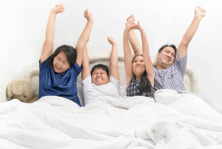 Asian Happy family waking up with raised hands, feeling good in the morning at home.の写真素材