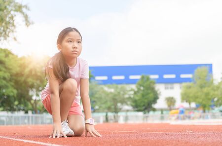 Cheerful cute girl in ready position to run on track, healthy and exercise concept..の写真素材
