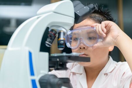 Little Scientist researcher using microscope in laboratory. Medical healthcare technology and...