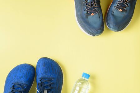 Two running shoes and bottle of water on yellowの写真素材