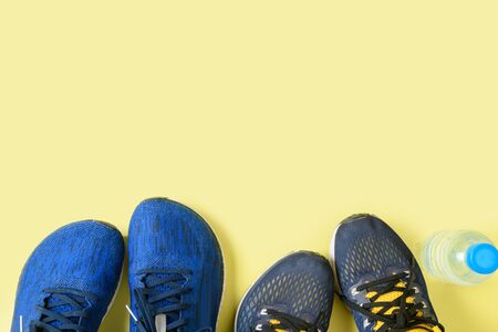 Two running shoes and bottle of water on yellow background, sport and healthy concept.の写真素材