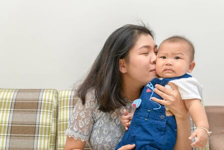 Mother is kissing baby son on cheek, Surprise emotion concept.の写真素材