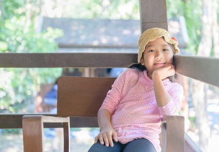 Cute asian girl smile and sitting on old chair, relaxation and travel on hoilday concept.の写真素材