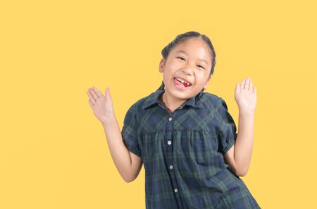 Portrait of happy smiling child girl isolated on yellow background.の写真素材