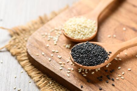 Black and White sesame seeds in a wooden spoon on wood table.の写真素材