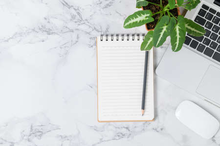 Pencil on blank notebook with laptop and mouse on marble table background, top view and copy space,...