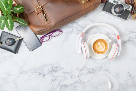 Coffee with headphone and vintage Leather bag, smartphone and vintage camera on marble table background, travel concept and copy sapce for input text.の写真素材
