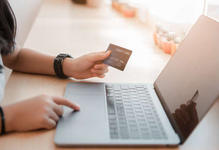 Hand girl holding credit card and using laptop, shopping online conceptの写真素材