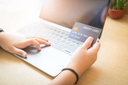 Hand girl holding credit card and using laptop, shopping online concept
