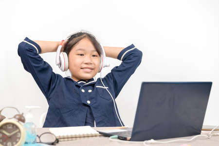 Cute and happy little girl children wear headphone and using laptop computer, studying through online e-learning system.の写真素材