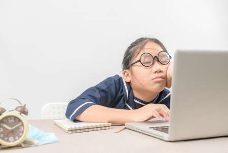 Tired student girl with glasses sleeping at desk in front of laptop after a hard day studying online., no energy left, education and new normal conceptの写真素材