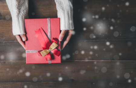 Little hands give gifts on Christmas Day. wood and snow background with copy space.